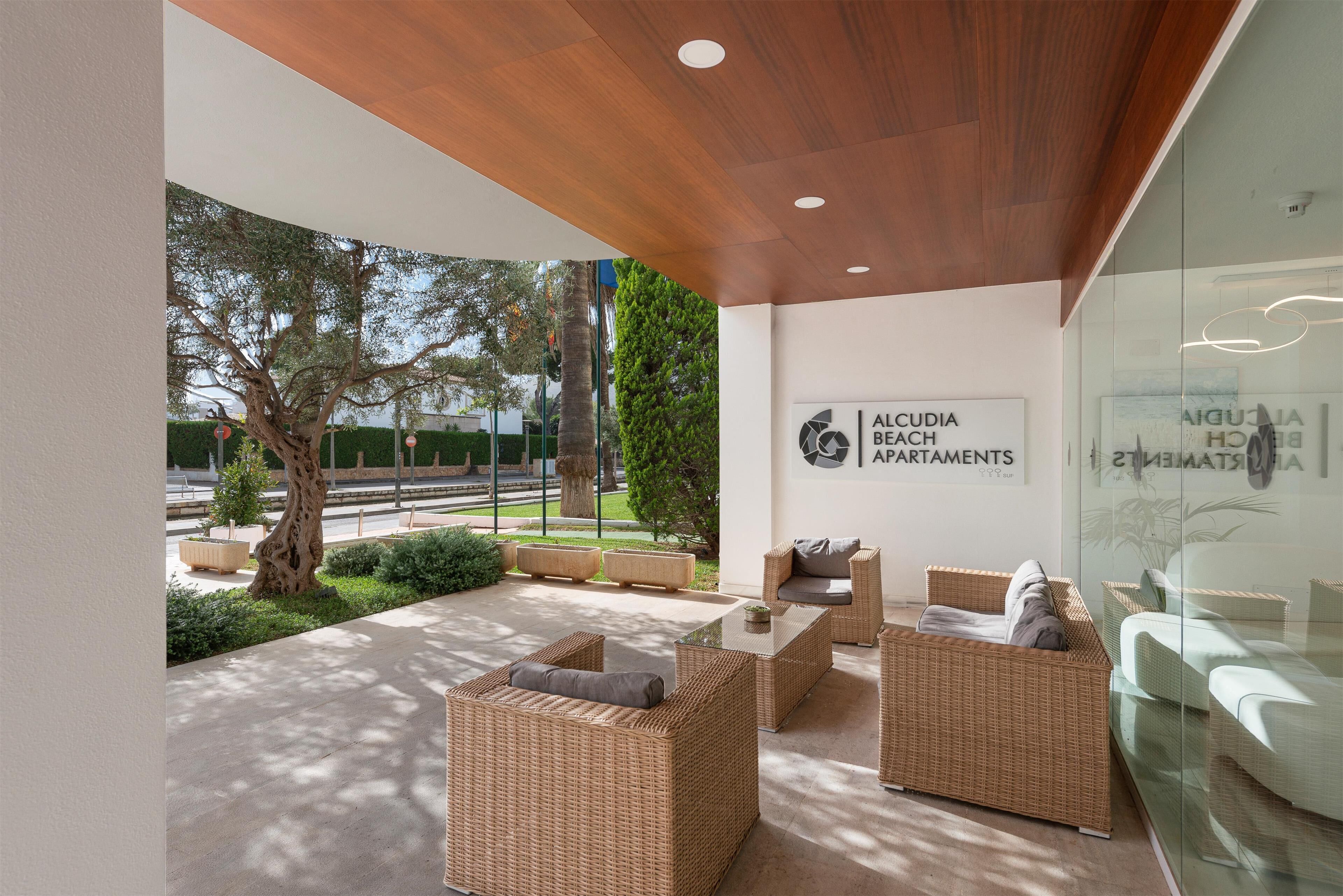 A modern outdoor seating area with wicker furniture and a glass wall.