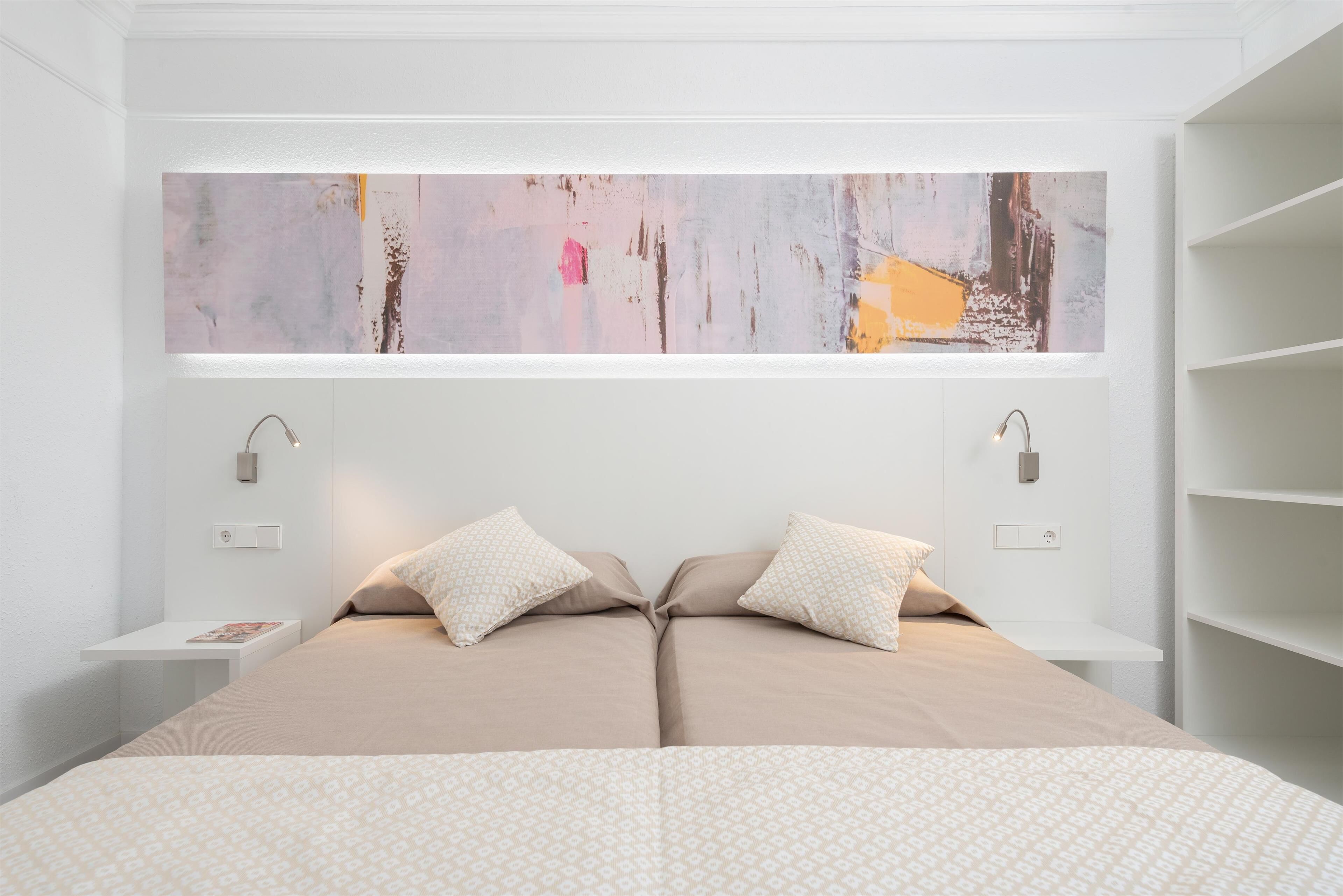 Een moderne slaapkamer met een groot bed, twee nachtkastjes en een groot abstract schilderij erboven.