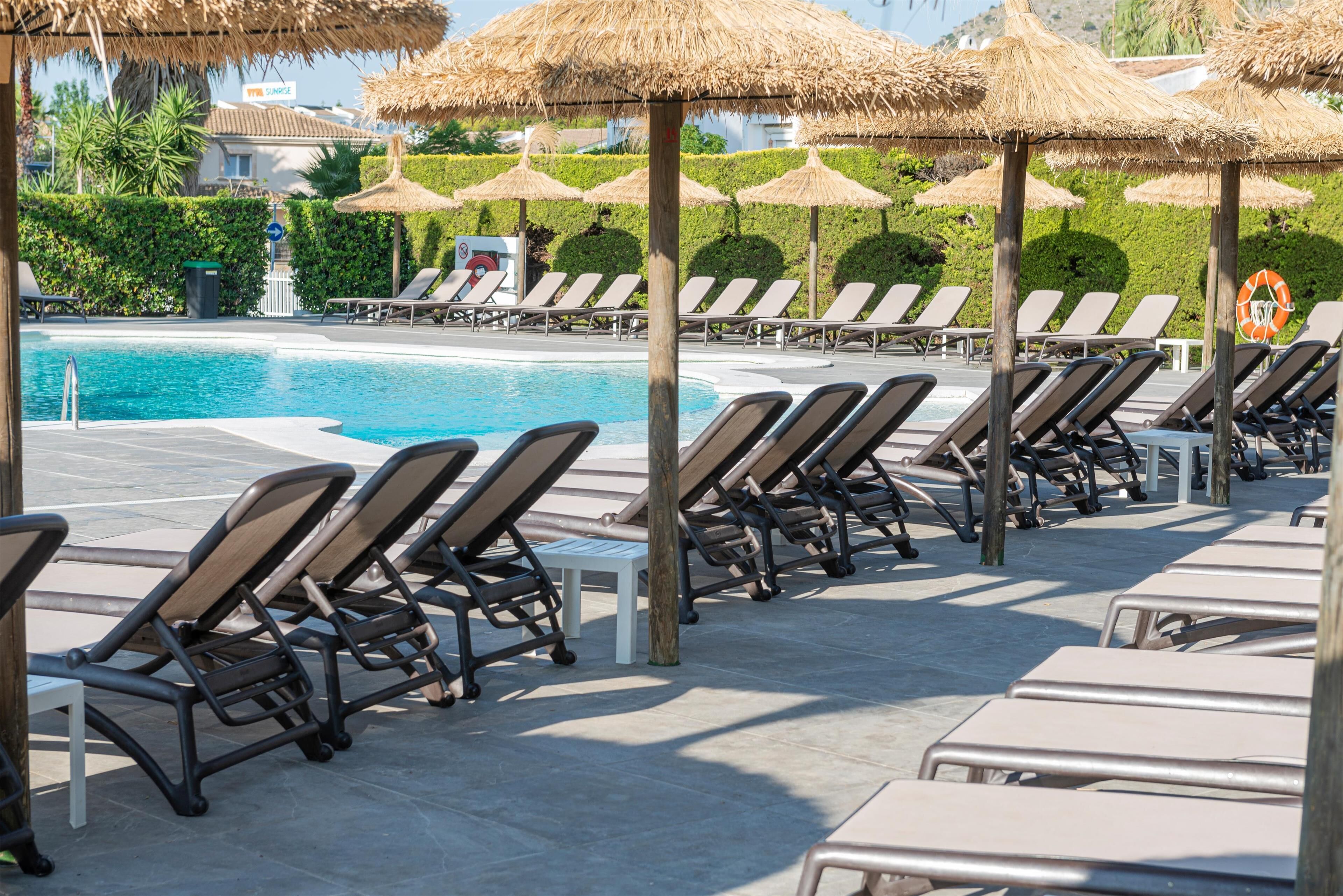 A poolside area with lounge chairs and thatched umbrellas.