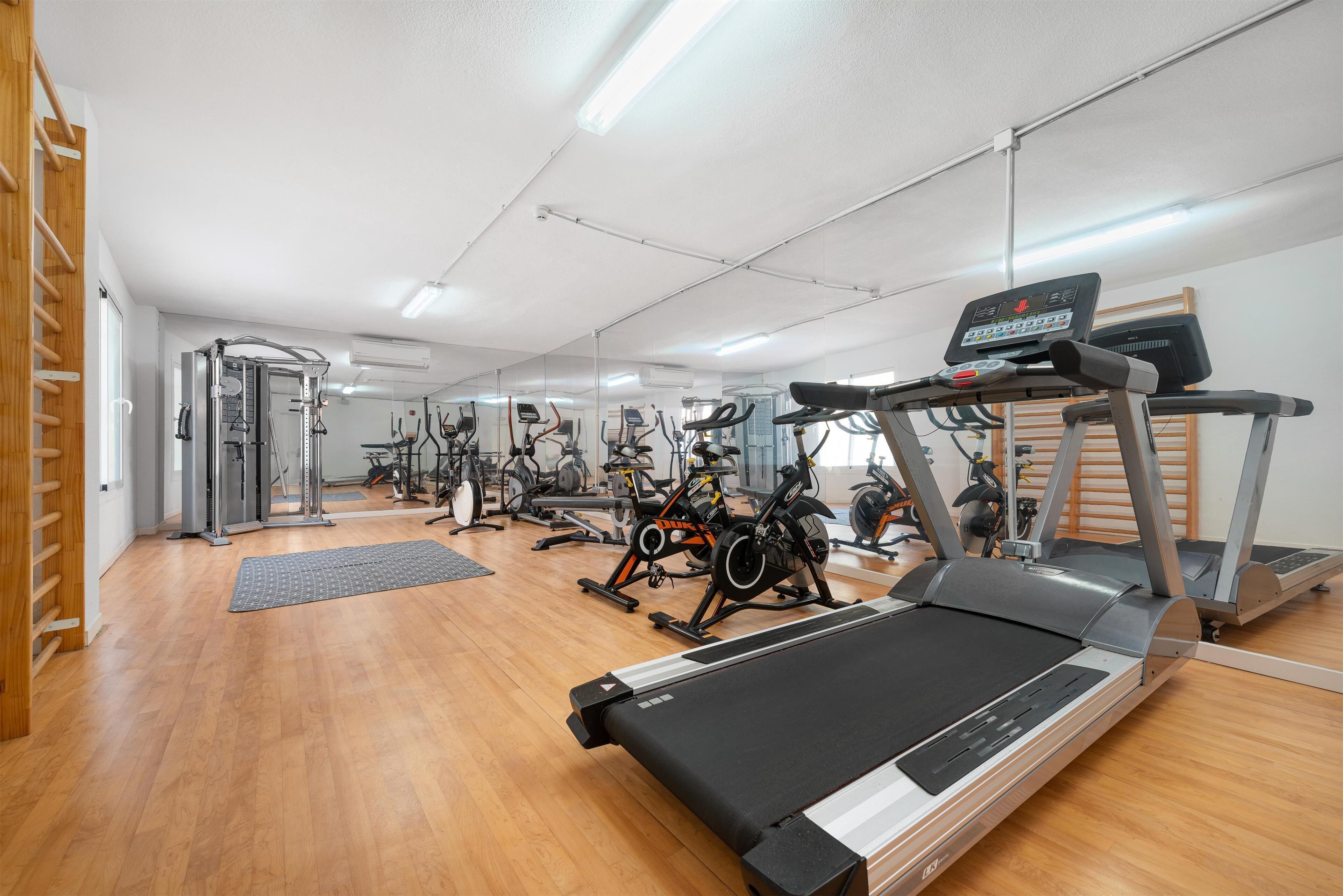 Un gimnasio con cintas de correr, bicicletas estáticas y máquinas de pesas.