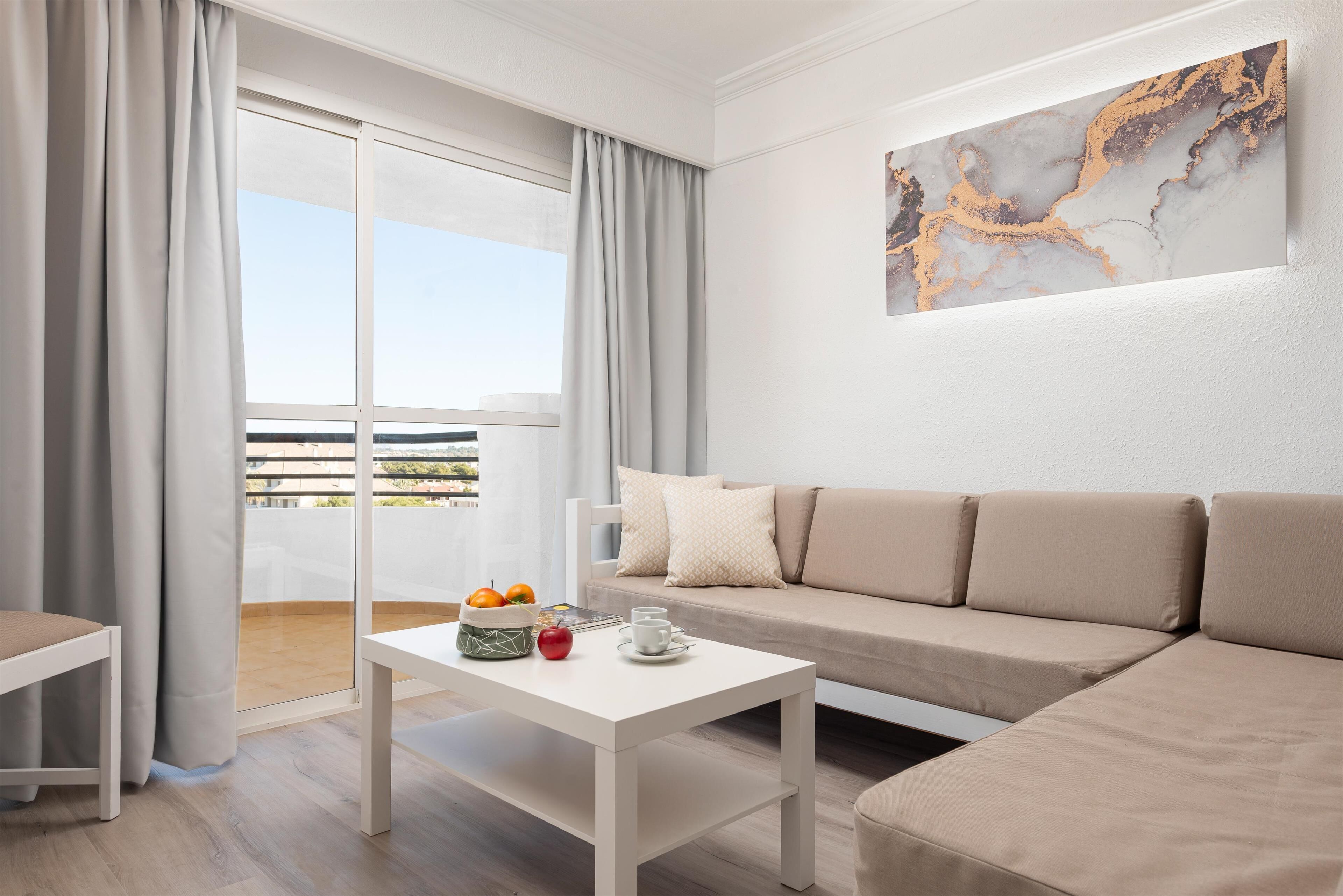 A modern living room with a sofa, a coffee table, and a balcony with curtains.
