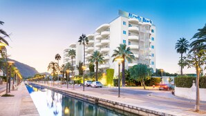 Un hotel con piscina, palmeras y una montaña al fondo.