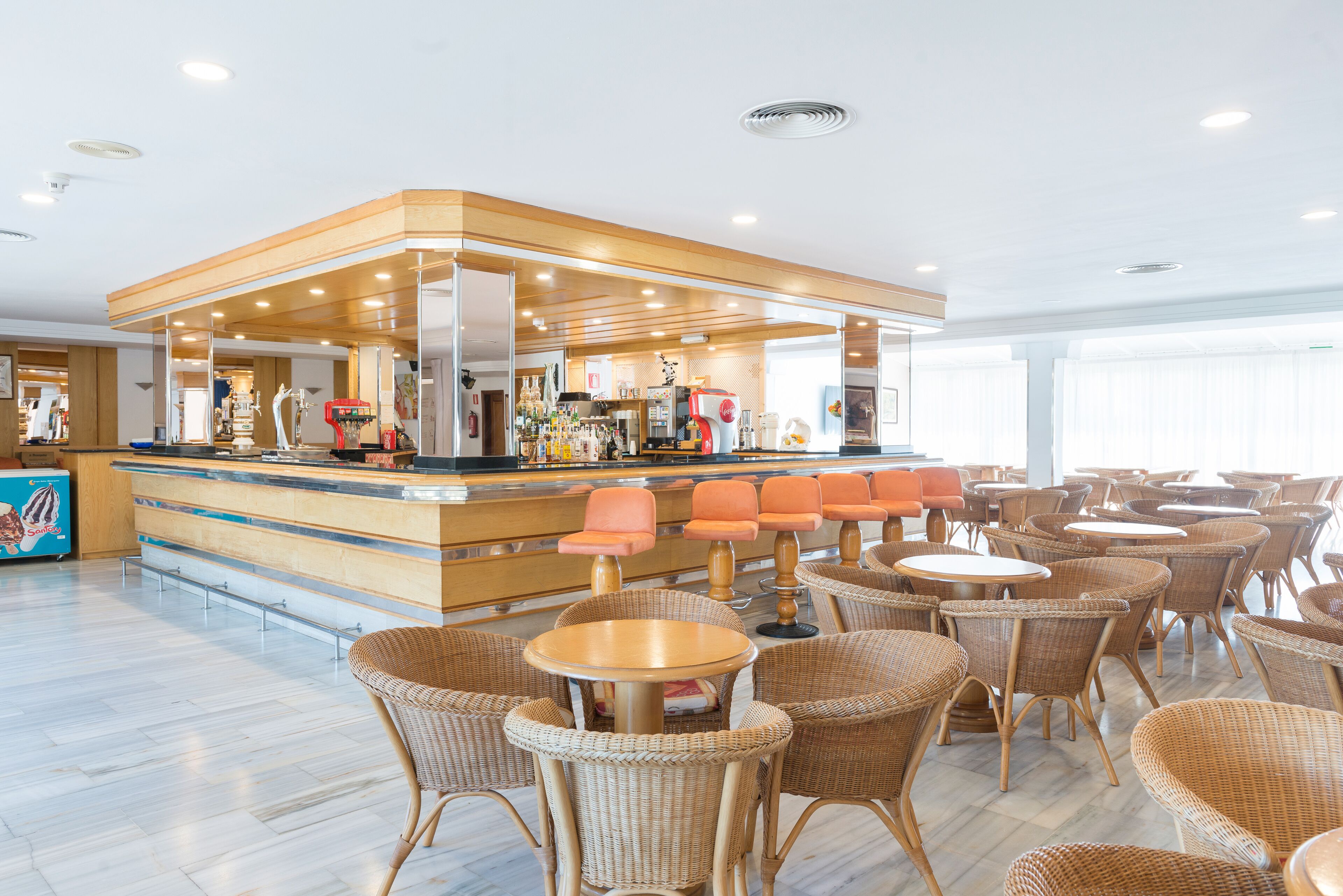 Een hotel lobby met een bar, rieten meubels en een strak, modern design.