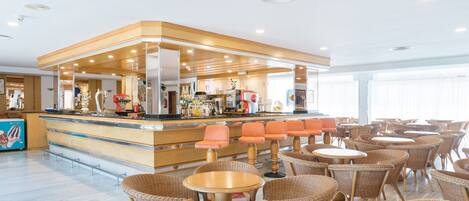 Een hotel lobby met een bar, rieten meubels en een strak, modern design.