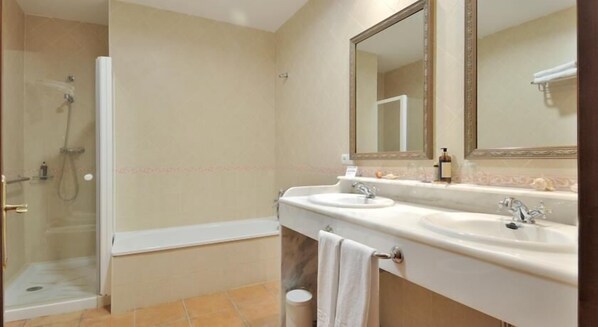 A bathroom with a glass-enclosed shower, two sinks, and a large mirror.