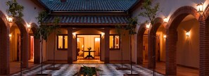 A courtyard with a checkered floor, brick arches, and a tiled roof. - Finca La Fronda (Alajar)