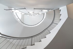 Una escalera de caracol de diseño moderno, con barandilla curva y una serie de luces a lo largo de la baranda.