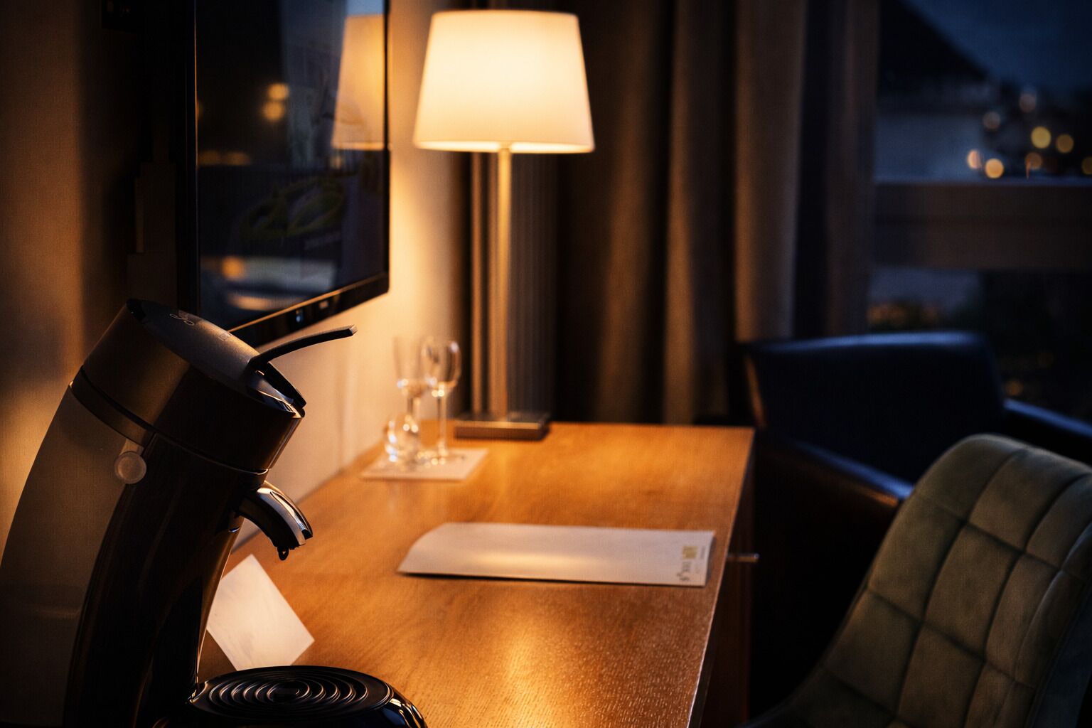 Une chambre d’hôtel équipée d’un bureau, d’une lampe, d’une chaise et d’un téléviseur.