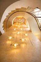 Una escalera de caracol de diseño moderno, con una serie de bombillas colgantes a lo largo de los escalones.