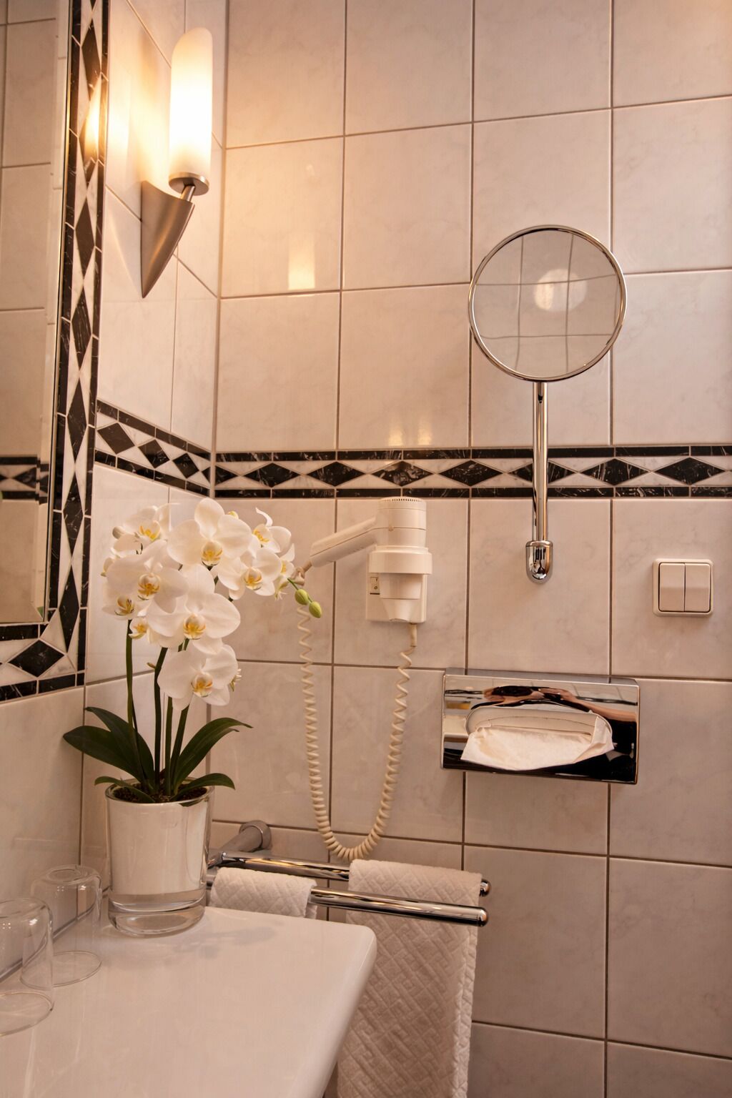 A bathroom with a shower, a towel rack, a mirror, and a potted orchid.