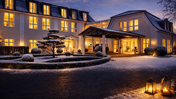 A hotel with a symmetrical facade, multiple windows, and a snow-covered garden with a central tree. - Hotel Sonne Rheda Wiedenbrück (Rheda-Wiedenbruck)