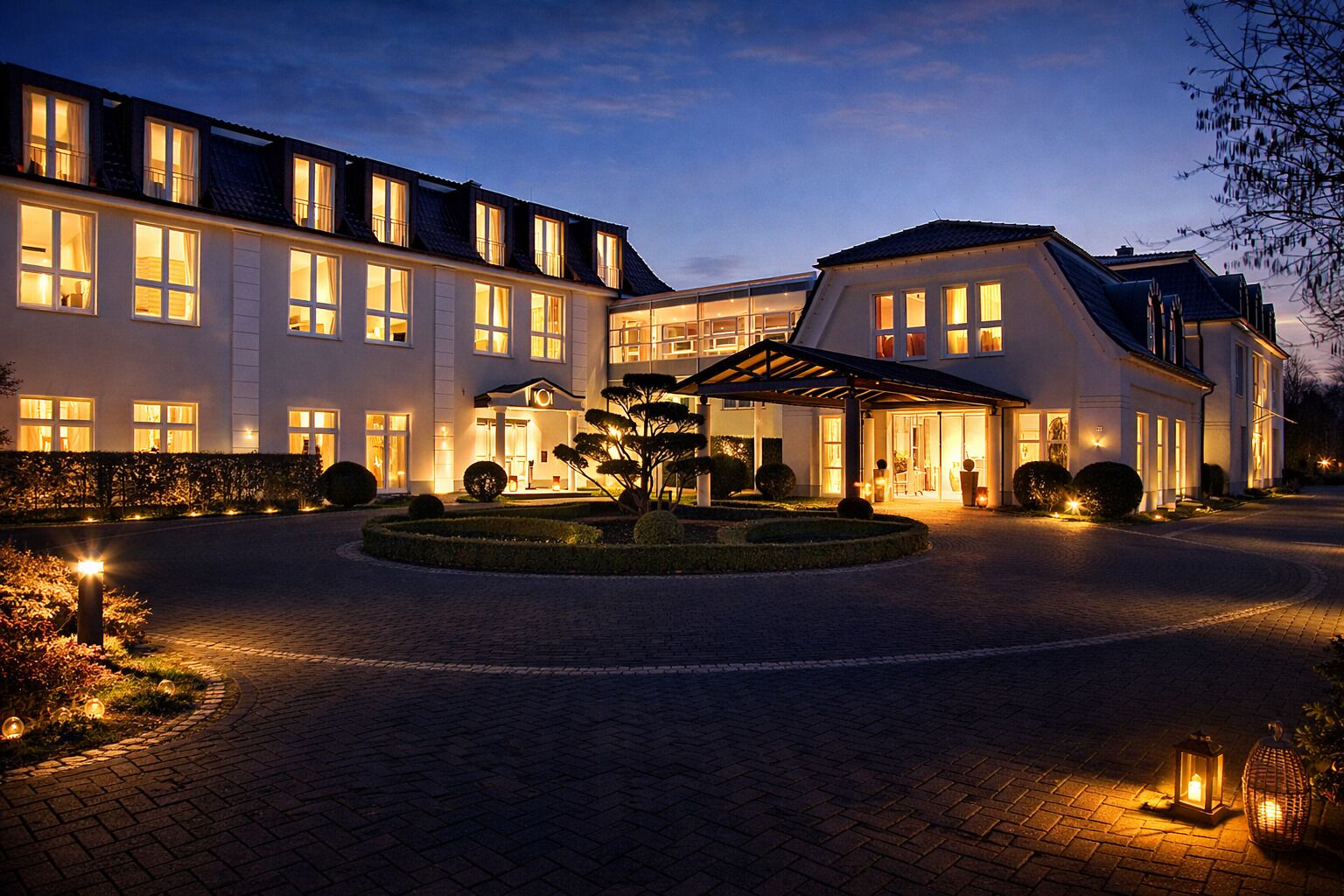 A large, modern hotel with a well-lit entrance and a landscaped garden.