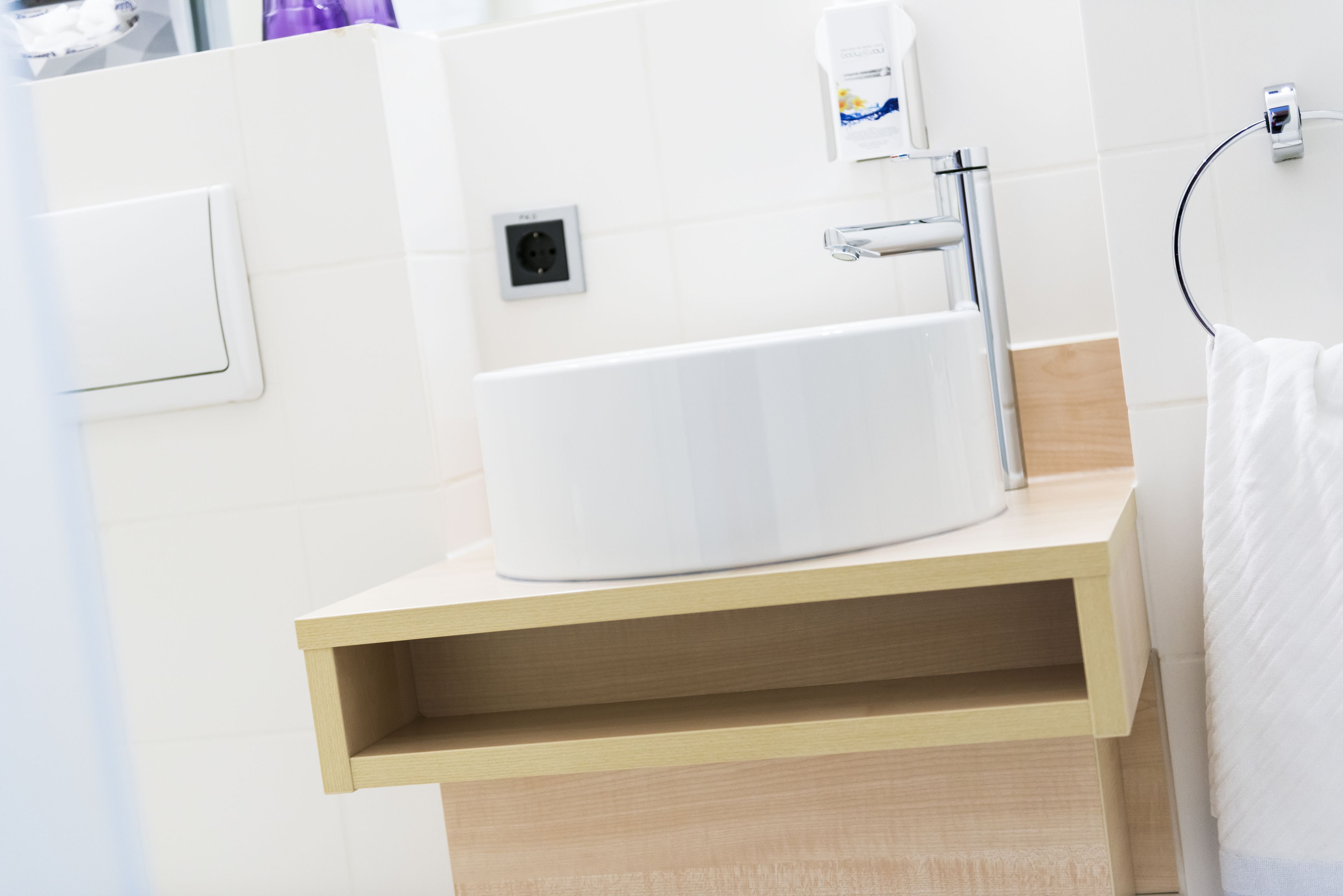 A bathroom with a white sink, a towel rack, and a soap dispenser.