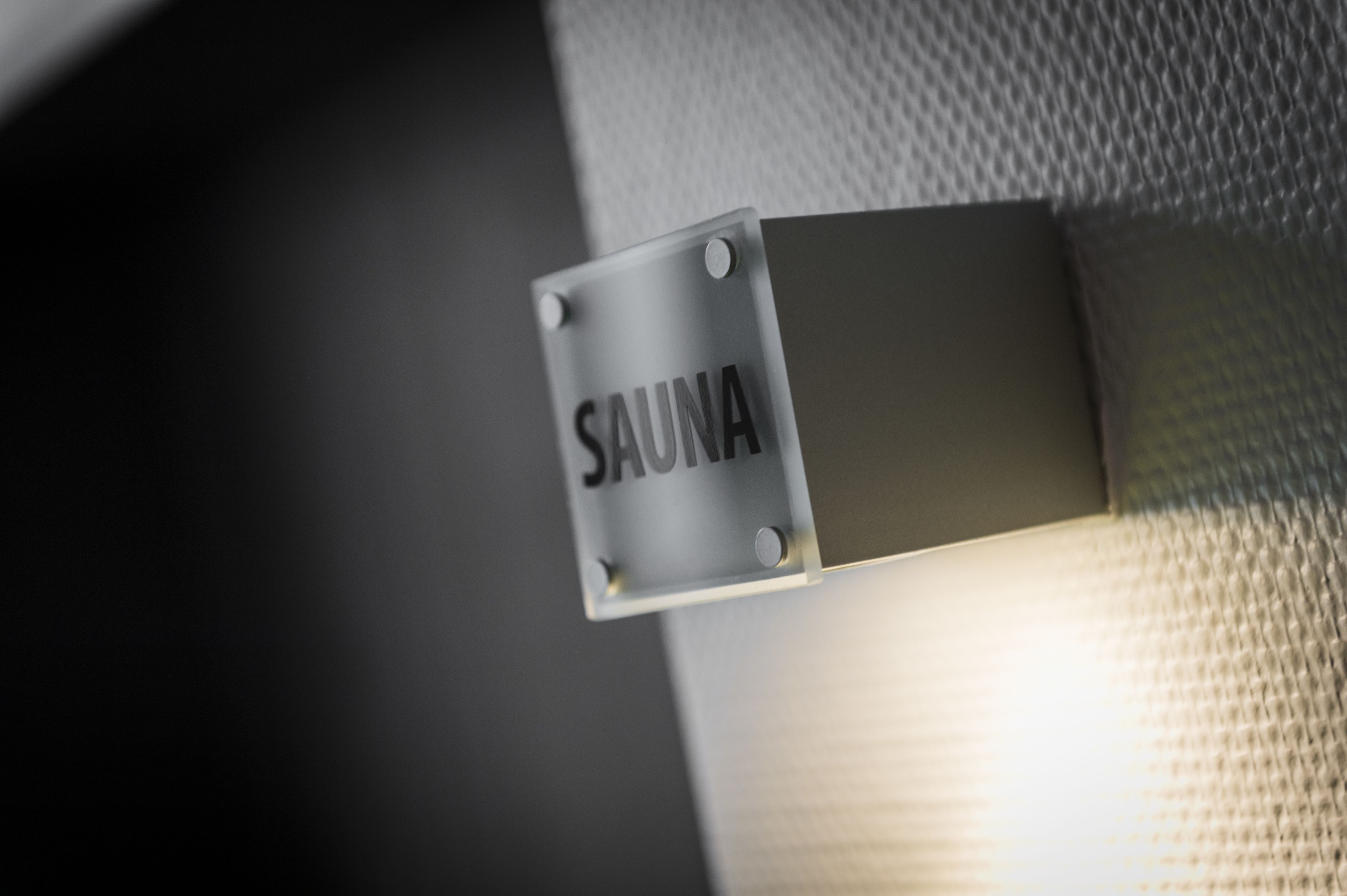 A sign labeled "SAUNA" attached to a textured wall.
