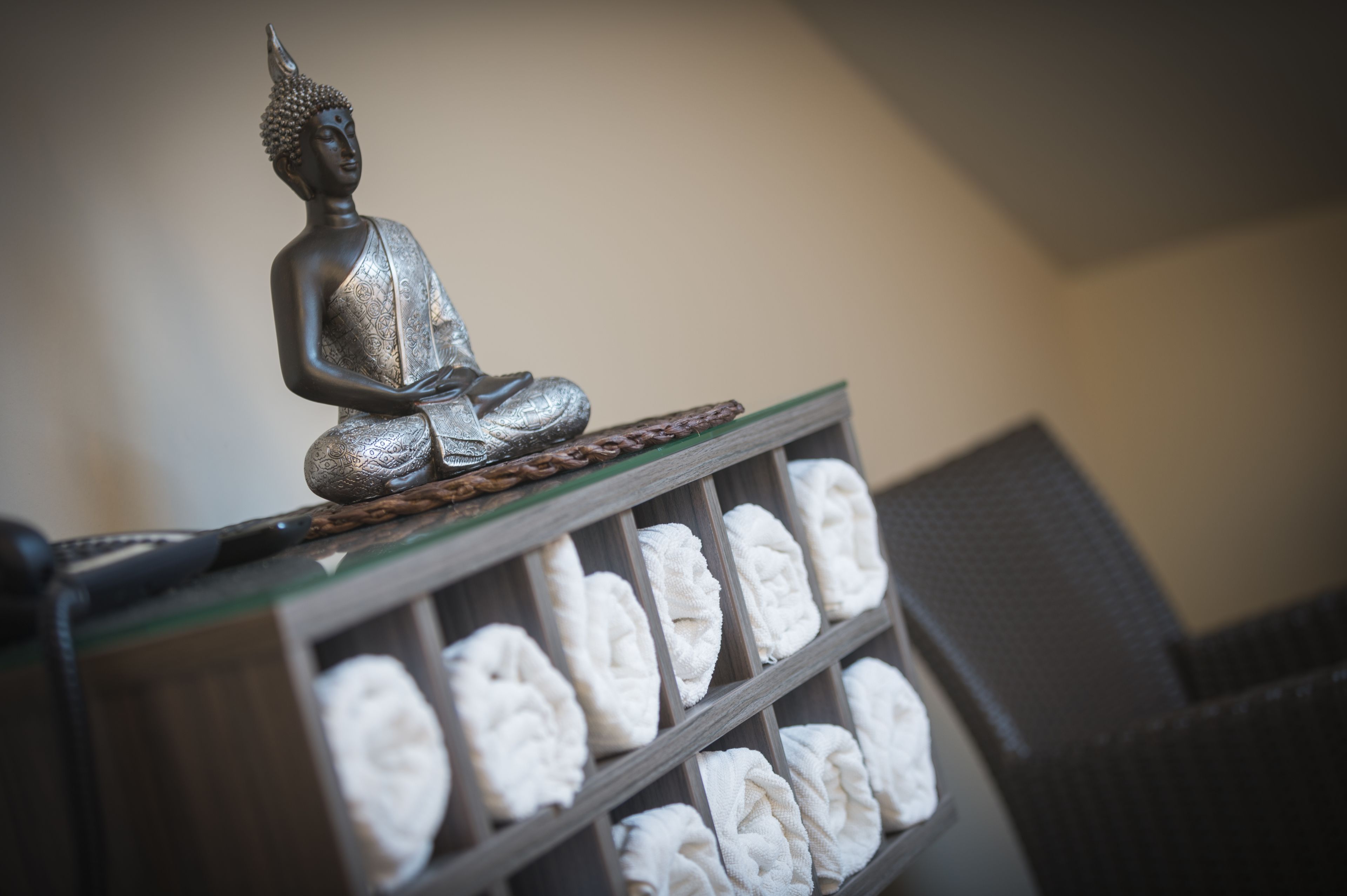 A statue of a seated figure on a shelf above a row of folded towels.