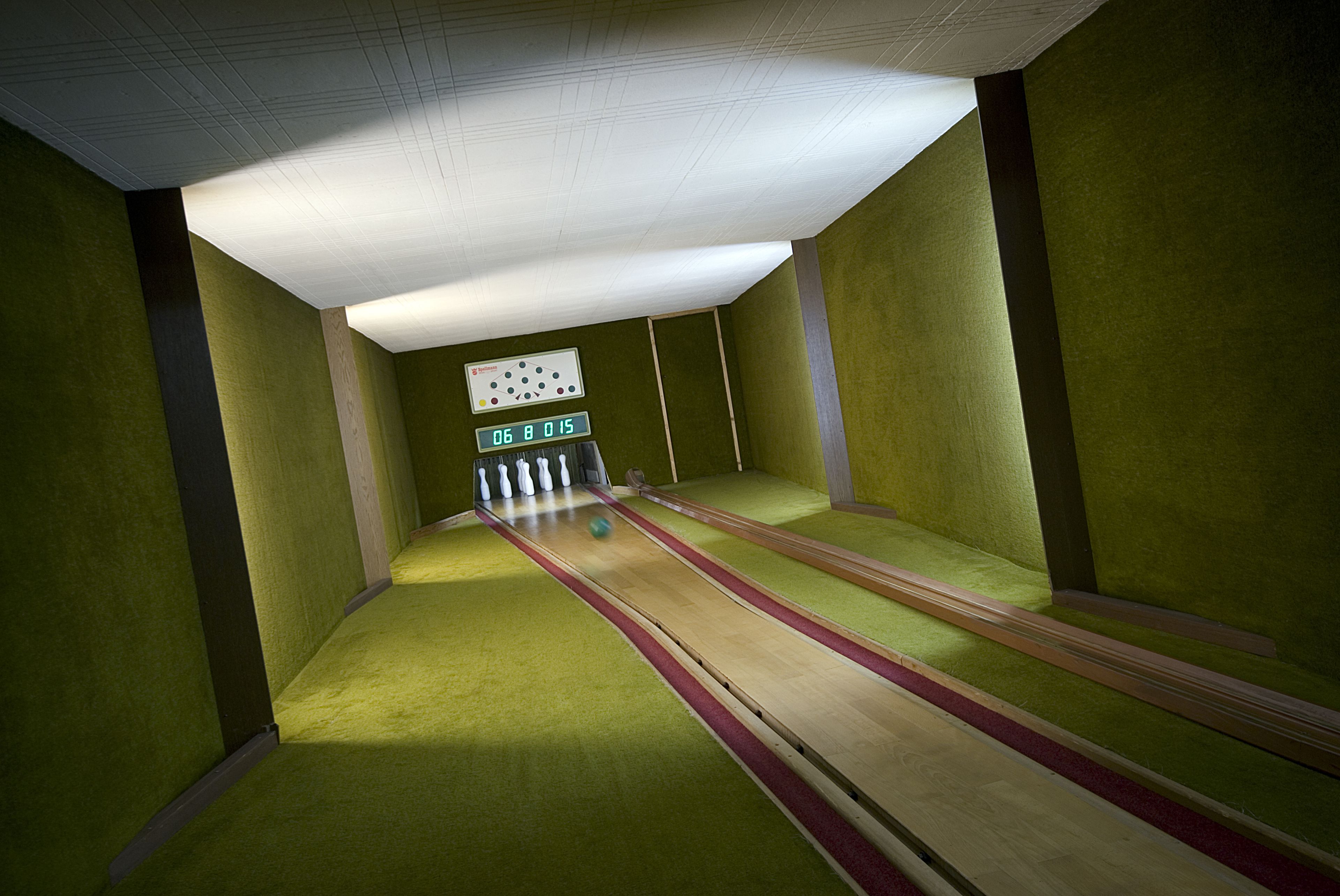 A bowling alley with green walls and a wooden floor.