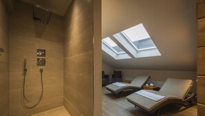 Un baño moderno con ducha y un tragaluz sobre una zona de estar.