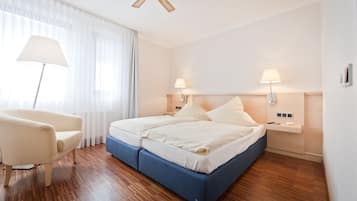 A hotel room with a large bed, two bedside tables, a chair, and a ceiling fan.
