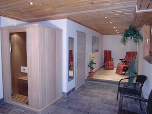 Relax in a spacious room with a high ceiling, comfortable seating area, and a potted plant.