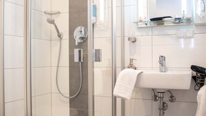 Une salle de bain moderne avec une douche en verre, un lavabo blanc et un miroir au-dessus du lavabo.