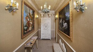 A hallway with two large paintings, a white fireplace, and wall sconces. - Residenza Horti Luculliani (Rome)
