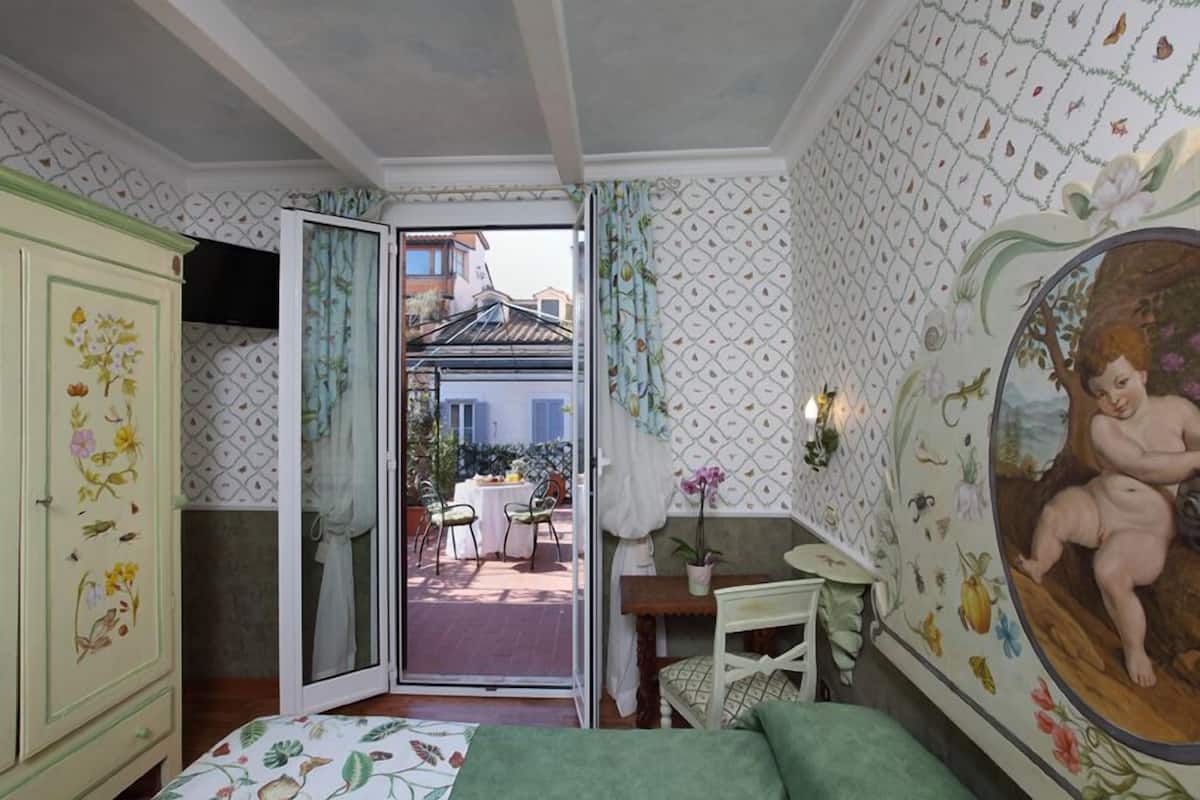 A bedroom with a bed, a wardrobe, a desk, and a view of the outside.