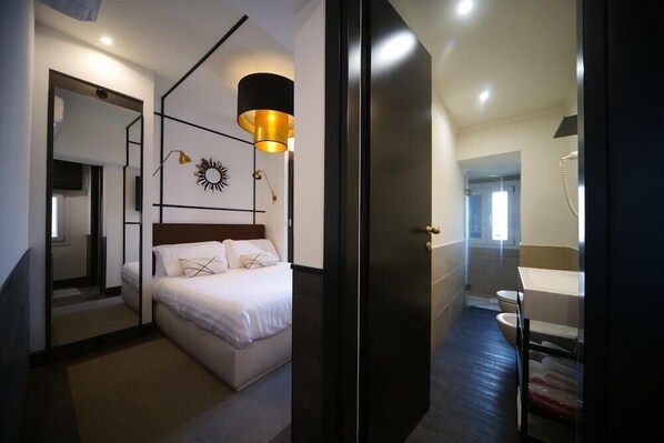 A modern hotel room with a large bed, a mirror, a ceiling light fixture, and a view of the bathroom. - Residenza Horti Luculliani (Rome)