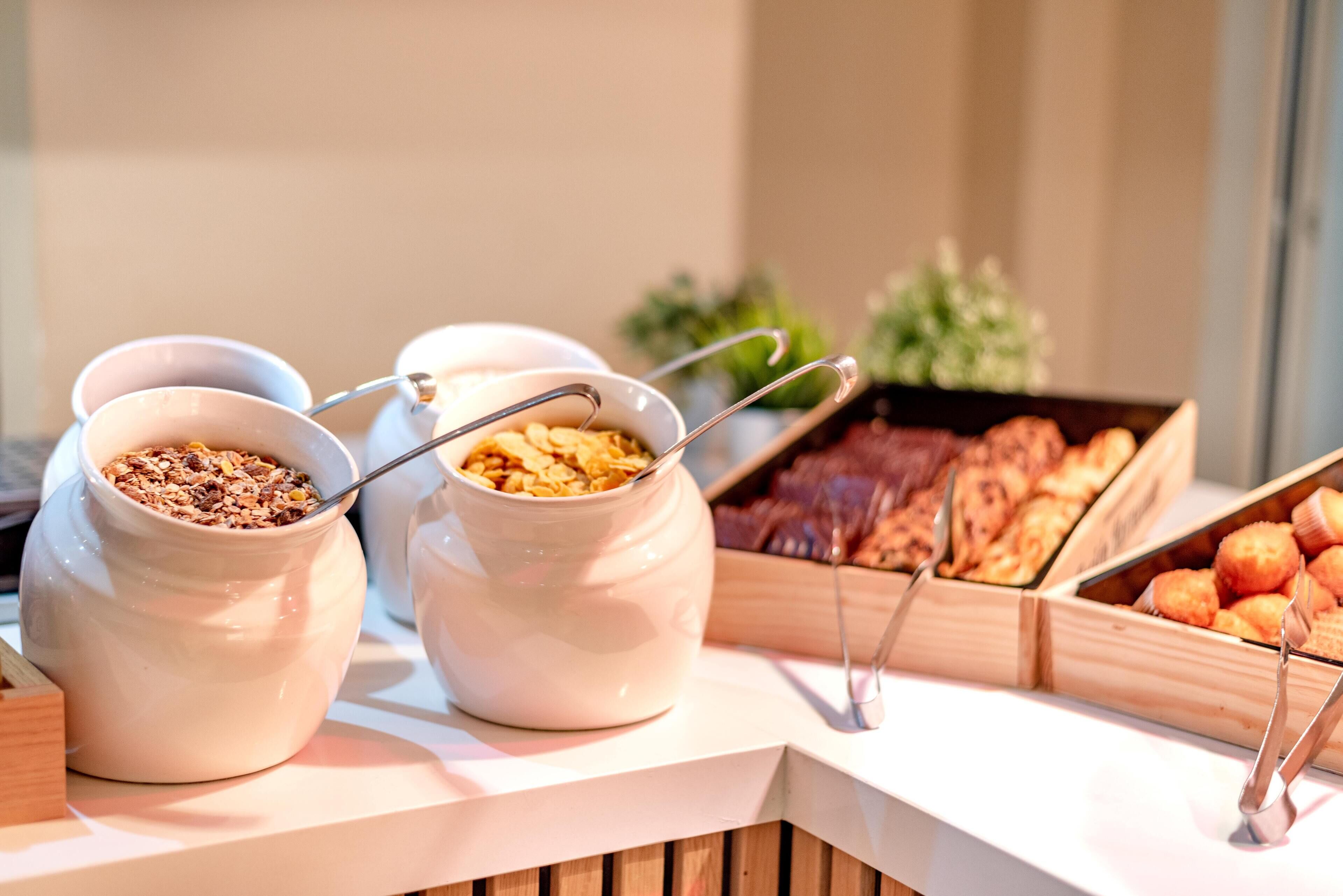 Un bufé con diversas opciones de comida, incluyendo granola, pastelería y platos de carne.