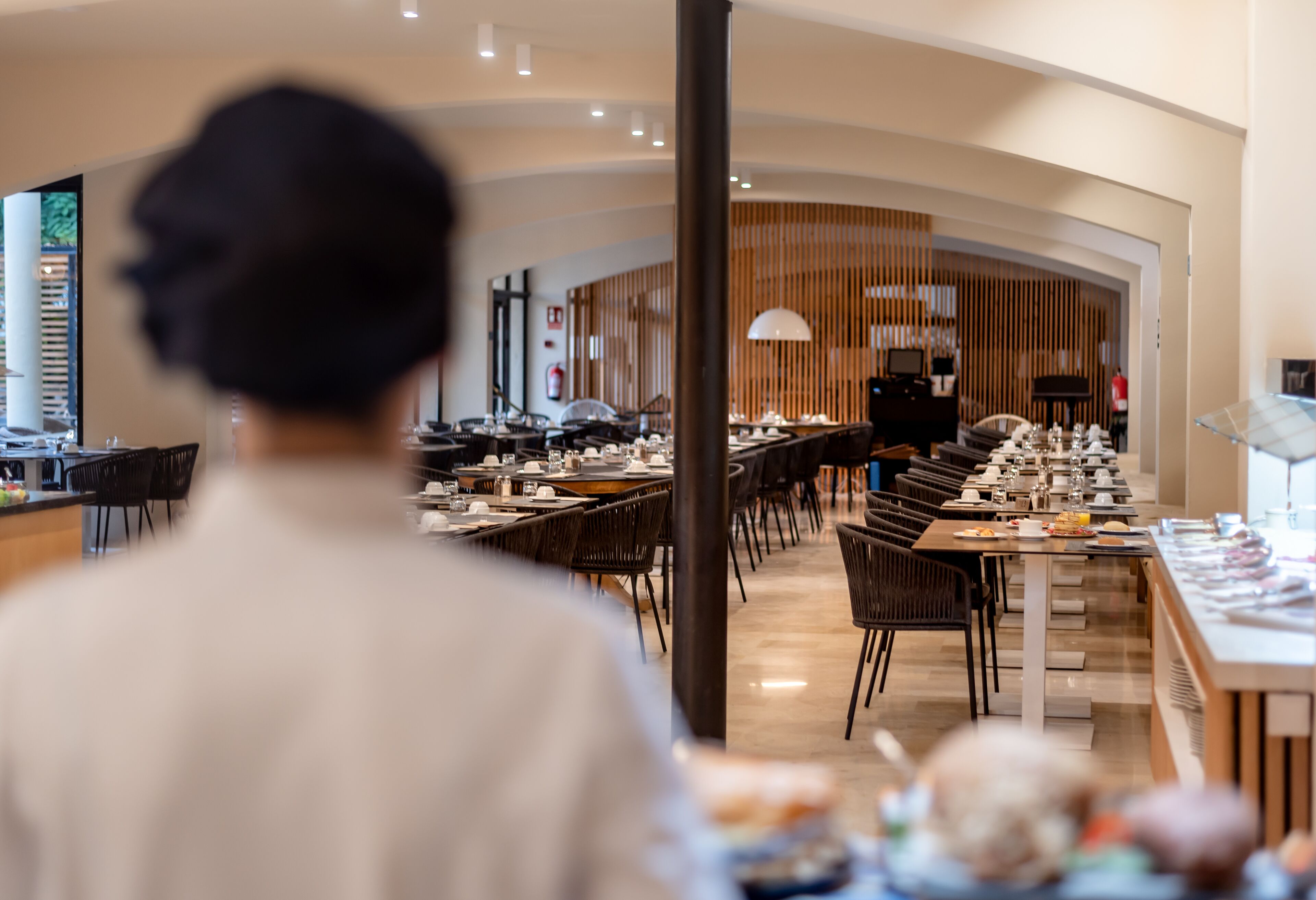 Un restaurante con una barra larga, varias mesas y sillas.