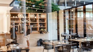 A modern restaurant with a spacious interior, featuring a mix of seating arrangements and a visible bar area.