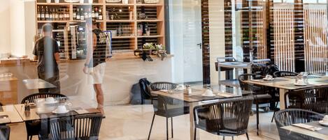 A modern restaurant with a spacious interior, featuring a mix of seating arrangements and a visible bar area.