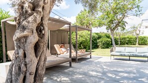 A modern outdoor seating area with a canopy, a cushioned bench, and a sofa.