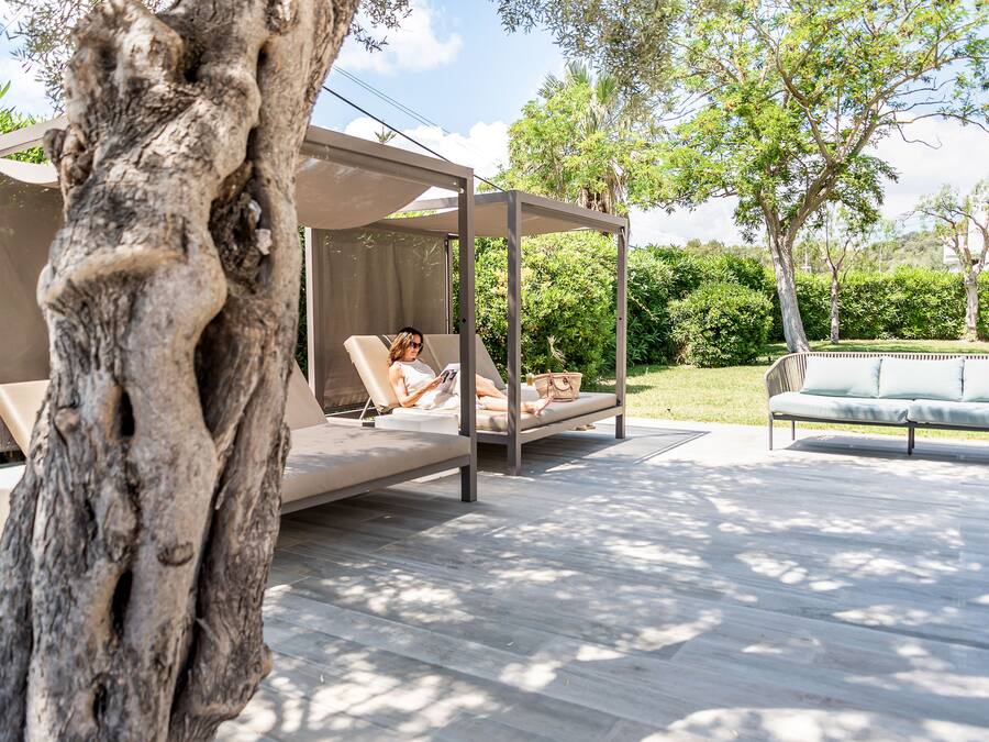 A modern outdoor seating area with a canopy, a cushioned bench, and a sofa.