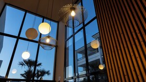 A modern interior with large windows, pendant lights, and a wooden slat wall.