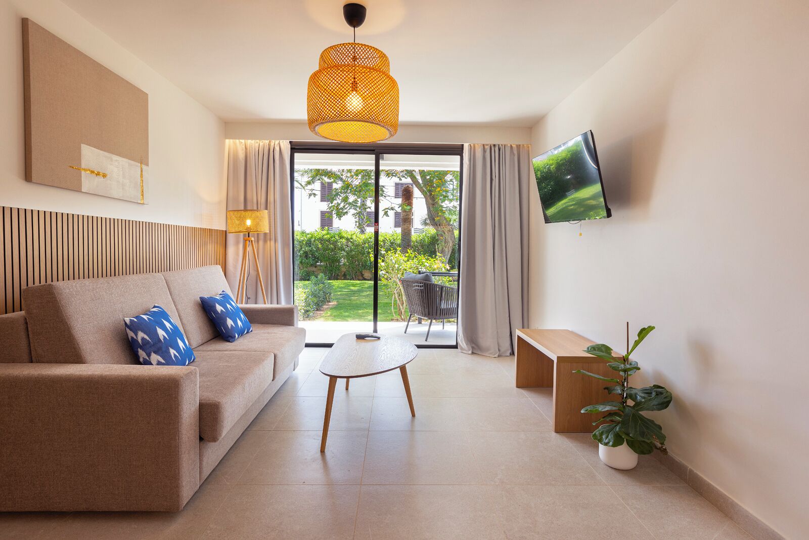 Una sala moderna con un sofá, una mesa de centro y un televisor montado en la pared.