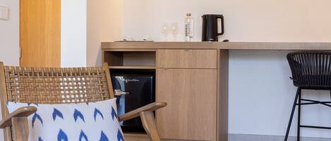 Una cucina moderna con frigorifero integrato, un tavolo da pranzo in legno e una sedia in vimini con cuscino decorato.