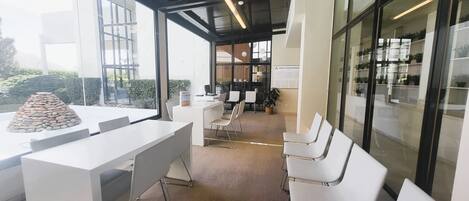 A modern office space with a reception area, a conference room, and a seating area with white chairs and a stone sculpture.