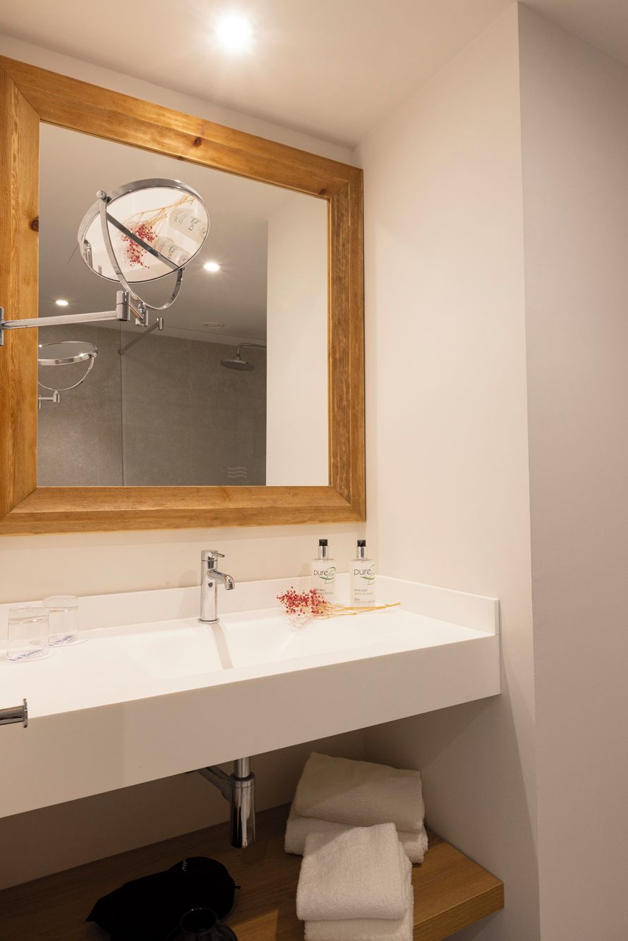 A bathroom with a wooden-framed mirror, a white sink, and a towel rack.