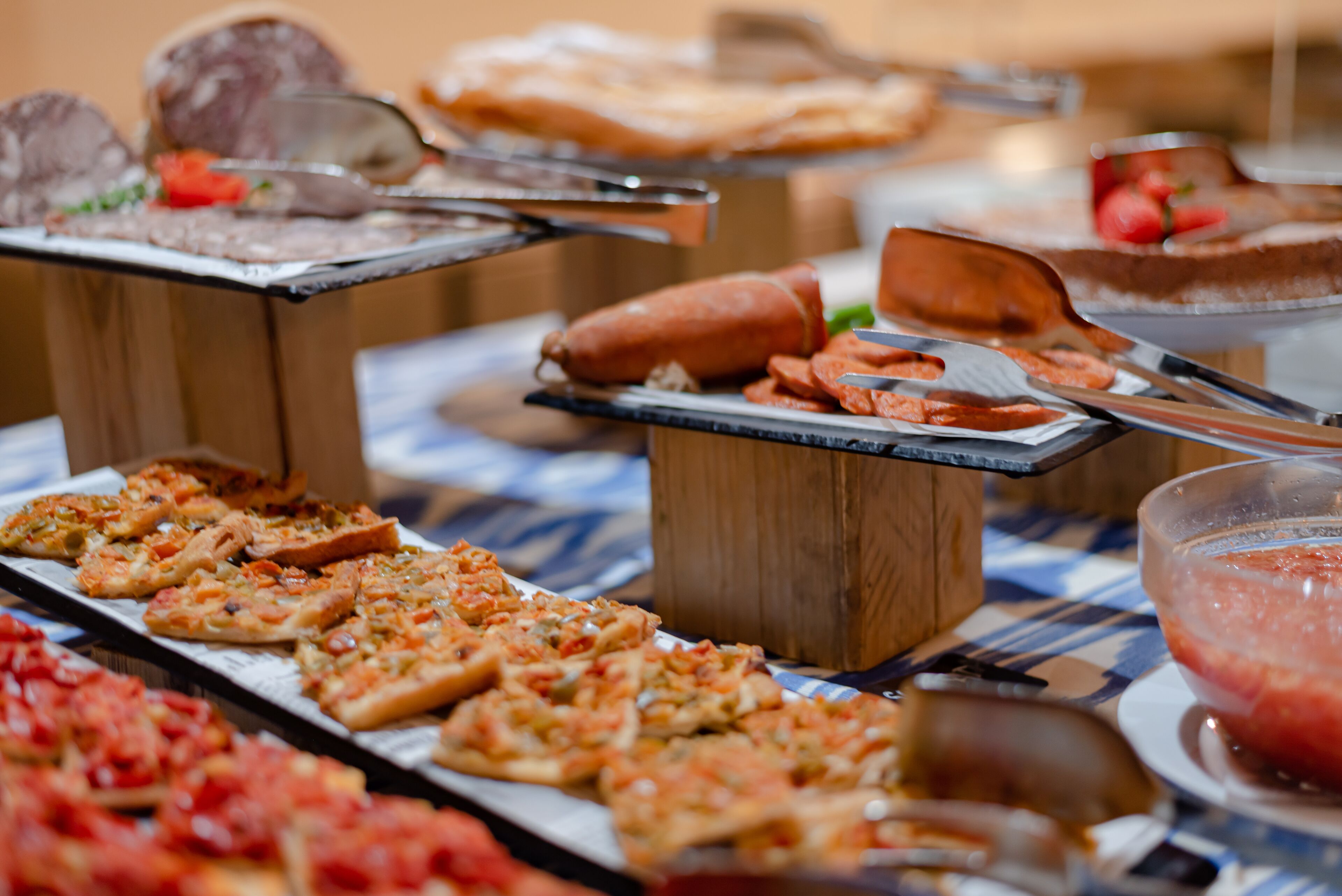 A buffet with various food items including pizza, hot dogs, and a fruit bowl.