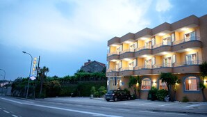 Un hotel de varios pisos con balcones, un área de estacionamiento y una señal de calle.