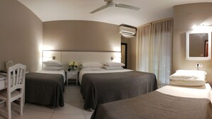 Habitación de hotel con dos camas, un escritorio, una silla, un ventilador de techo, un equipo de aire acondicionado y un espejo.