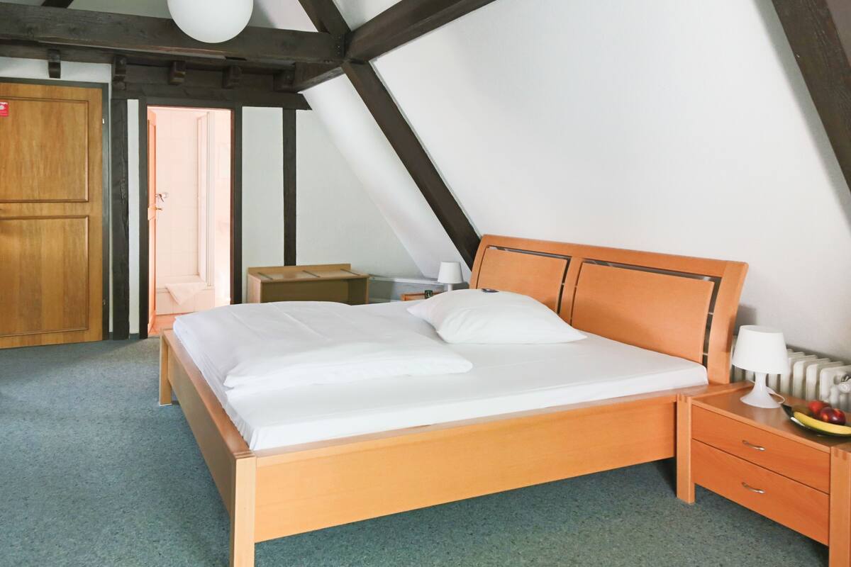 A bedroom with a wooden bed, a nightstand with a lamp, and a fruit bowl.