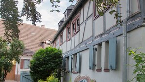 Un estrecho sendero adoquinado que conduce a un edificio tradicional con tejado de baldosas y contraventanas.
