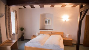 Un dormitorio con cama de madera, mesitas de noche, una planta en maceta y un aplique de pared.