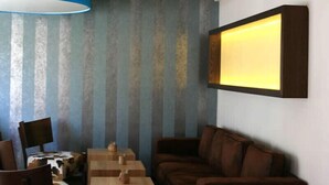 A room with striped wallpaper, a brown leather sofa, a wooden coffee table, and two blue lamps. - Hotel Thiesmann (Muelheim an der Ruhr)