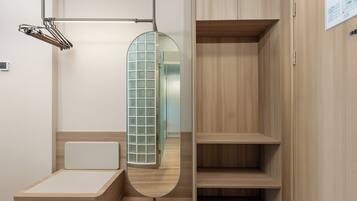 A minimalist room with a wooden bed, a mirror, and a wardrobe.