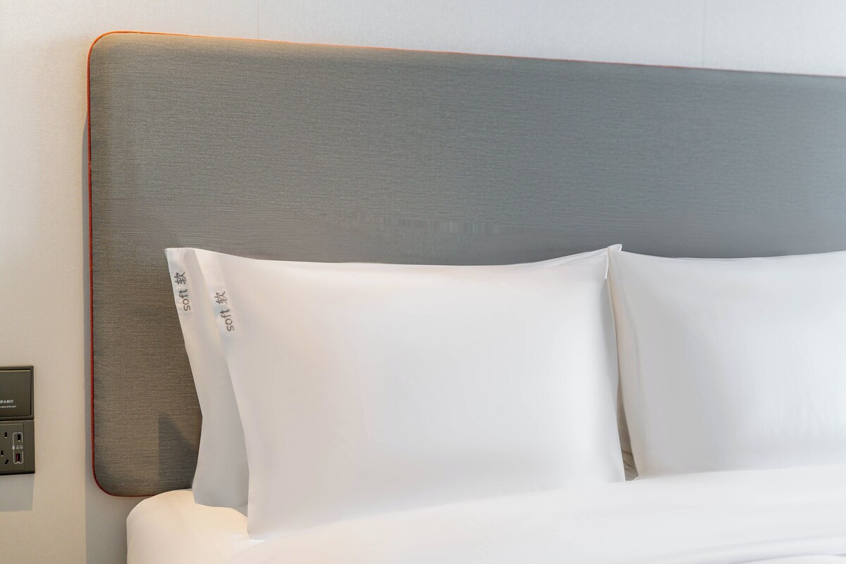A bed with white bedding and a grey headboard.