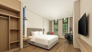 Ein modernes Hotelzimmer mit einem großen Bett, einem Einbauschrank, einem Schreibtisch, einem Stuhl und einem an der Wand befestigten Fernseher.
