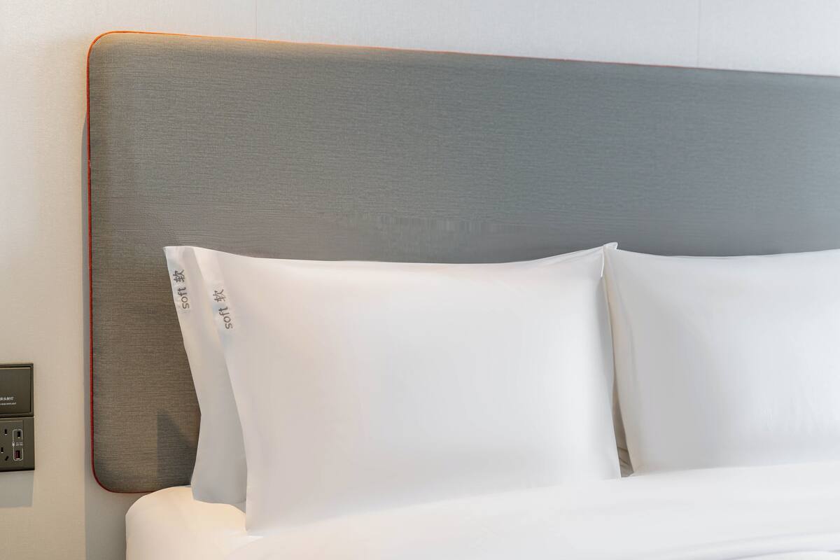 Ein Bett mit weißer Bettwäsche und einem grauen Kopfteil.