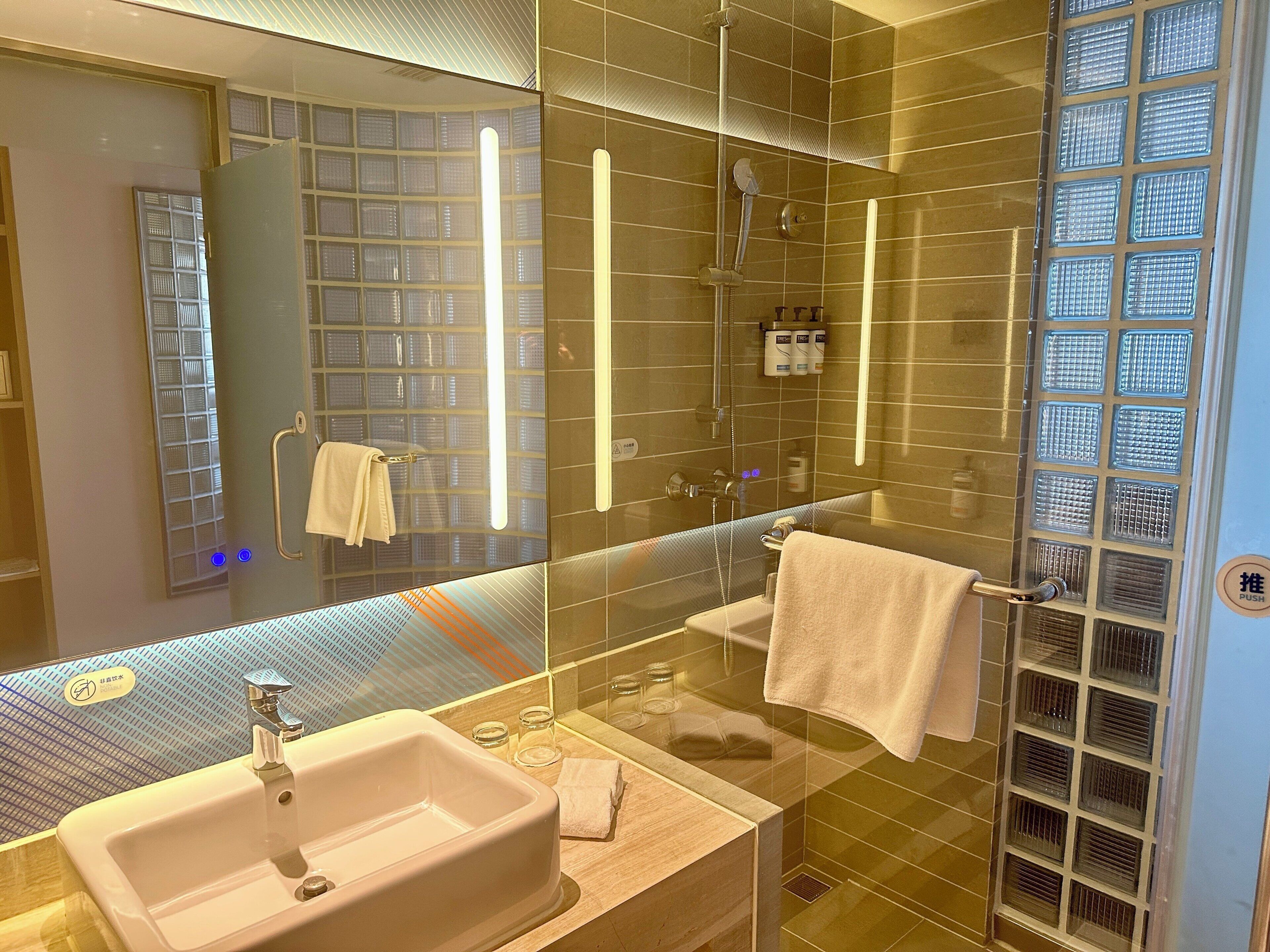 A modern bathroom with a glass shower enclosure, a sink, and a mirror.